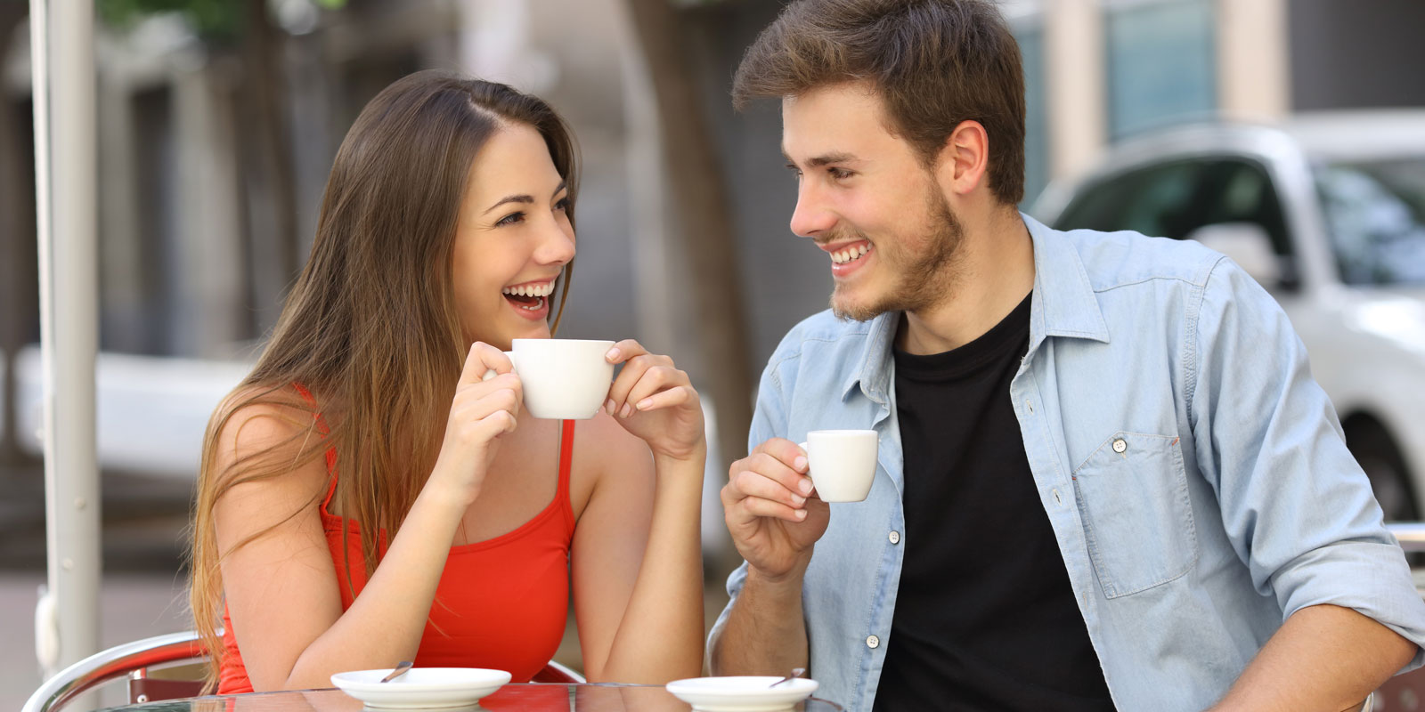 A man and woman are drinking coffee at an outdoor cafe.